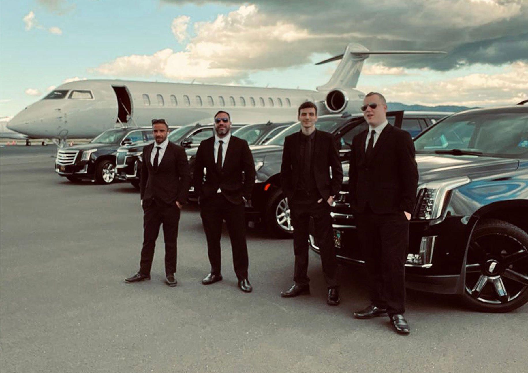 Chauffeurs standing next to their cars at private jet center