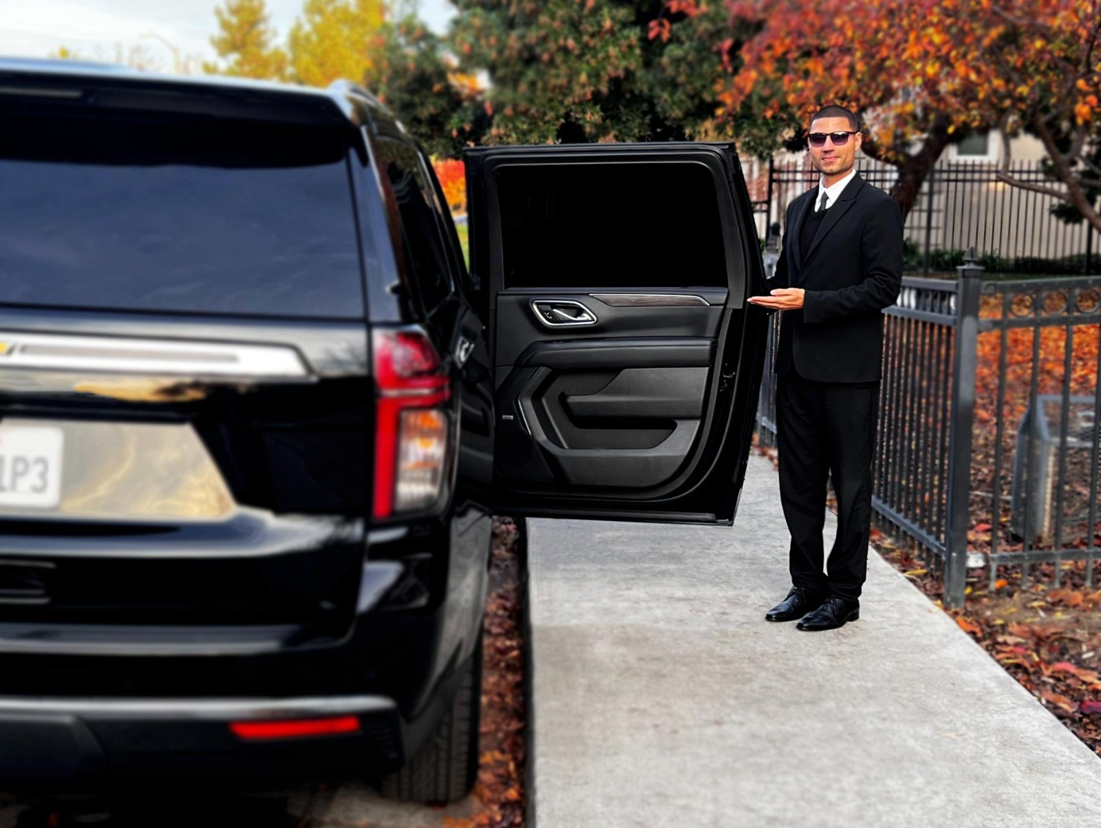 Driver in a suit opening the door for a customer in luxury SUV