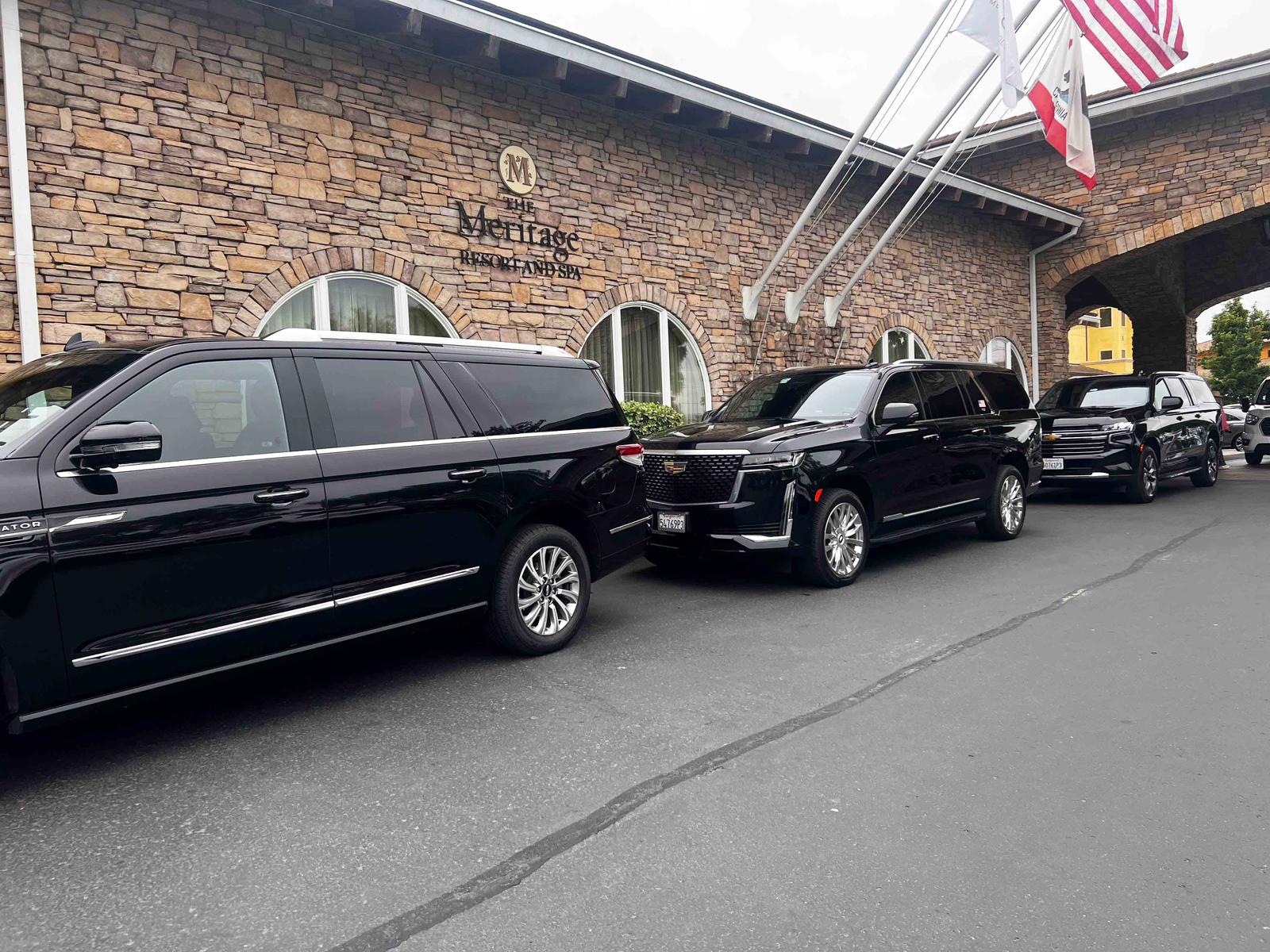 A fleet of luxury black SUVs parked outside The Meritage Resort and Spa, showcasing premium transportation services.